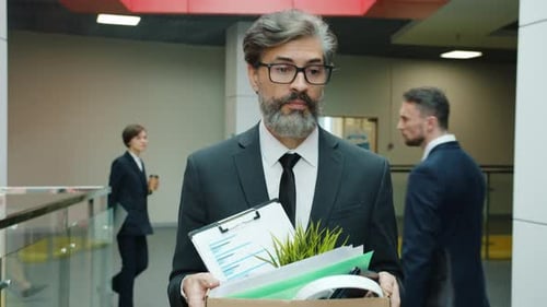 Slow Motion of Fired Businessman Walking in Hall with Box of Belonging After Dismissal