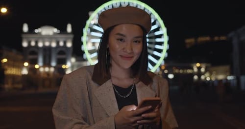 Female Person Using Smartphone While Standing at Night Street. Stylish Woman Raising Head and