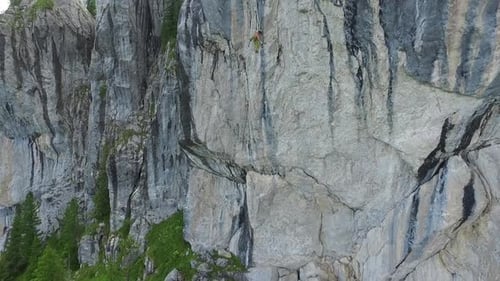 Aerial drone view of a man rock climbing up a mountain.