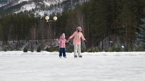 Mother and Daughter Ice Skating in Winter Landscape