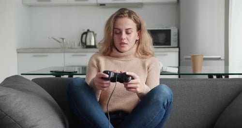 Blonde Frau, die emotional Video mit Joystick spielt