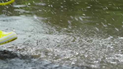 Child in Rain Boots Splashing in Puddle