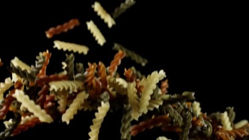 Rotini Pasta Macaroni vole après avoir explosé. Tas de pâtes multicolores Bouncing Black Bg