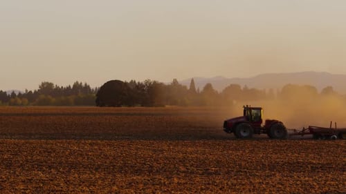 Tractor plowing field at sunset.