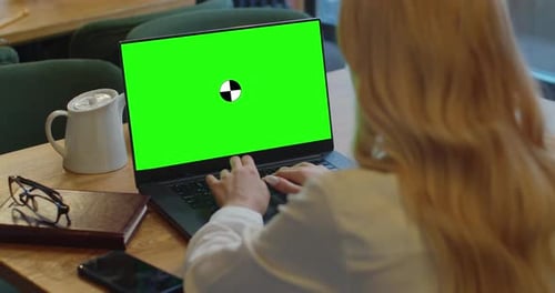 Woman Using Her Laptop with Blank Green Screen and Typing