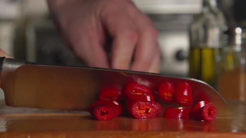 Chef Slicing Red Chili Pepper with Silver Knife