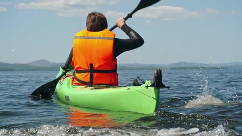 Kayaker Paddling Bright Green Kayak on Lake
