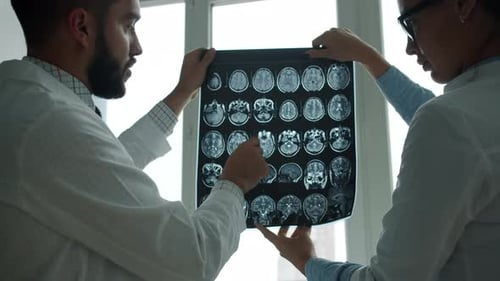 Man and Woman Doctors Studying MRI Images in Hospital Talking Discussing Health