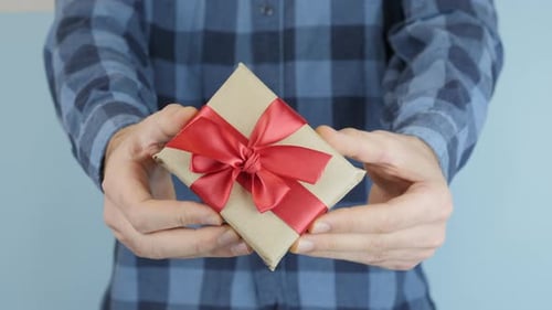 Person Holding Gift with Red Ribbon Up Close