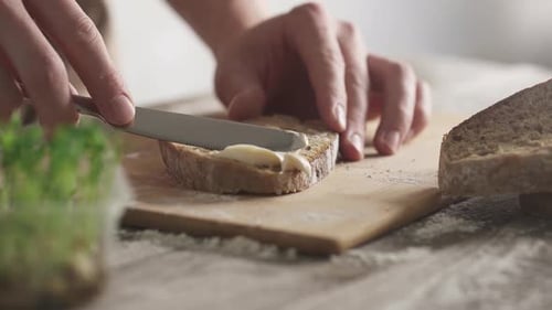 Hands Spreading Creamy Spread on Slice of Bread
