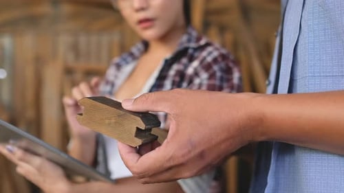 Close up hands of carpenter man or craftsman hold piece of wood product and discuss with woman