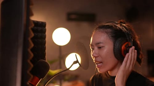 young woman singer or musician working for recording the music in studio, wearing earphones