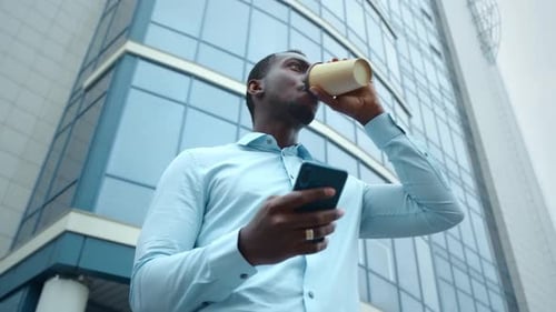 Portrait of Stylish Black African Man Walking Down the Street Using Smartphone for Social Media.