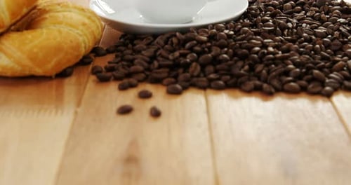 Close Up of Coffee Cup, Croissant, and Beans