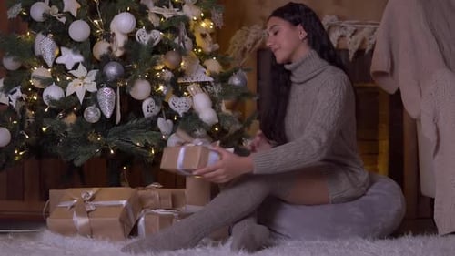Young Woman Enjoys Gifts by Christmas Tree