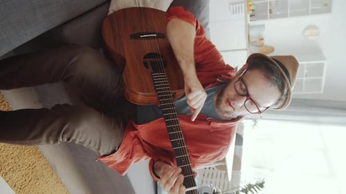 Man Playing Guitar on Sofa, Indoors