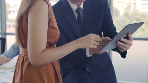 Responsable montrant le projet de plan sur une tablette à une femme d'affaires créative dans un bureau moderne.