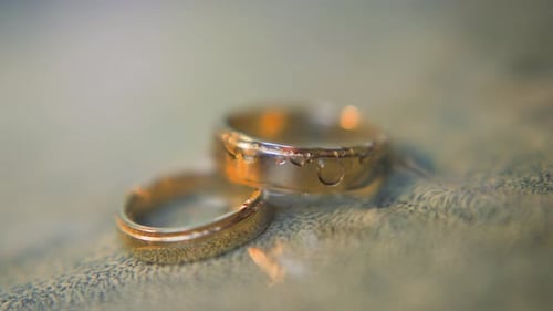 Elegant Pair of Gold Wedding Rings Lies in Clear Water