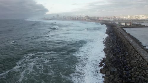 Dramatic Ocean Waves Crashing on Breakwater Near City