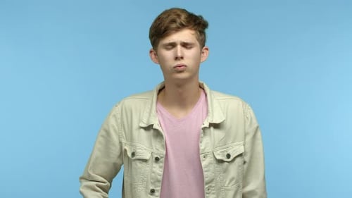 Zeitlupe eines verärgerten und verzweifelten jungen Mannes, der ausatmet und sich mit einer Fingerpistole in den Kopf schießt und