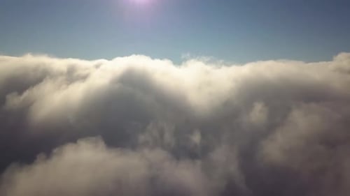 Aerial view from above of white puffy clouds in bright sunny day