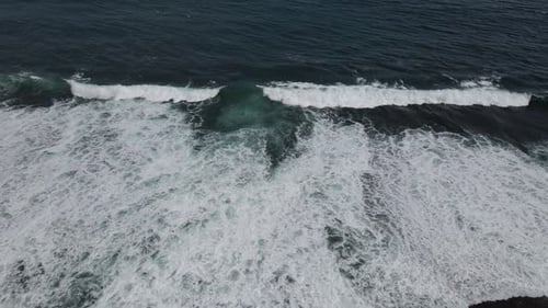 Top down aerial view of giant ocean waves crashing and foaming
