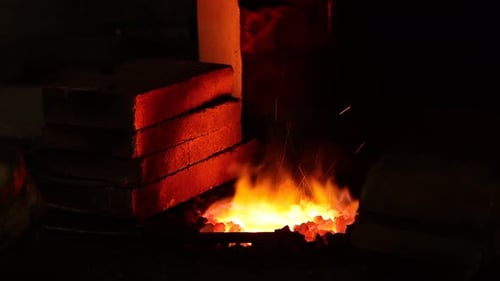 Intense Fire Heating Metal in Dark Workplace