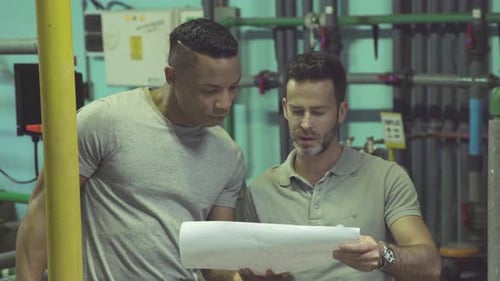 Industrial plant workers at work looking at blueprint