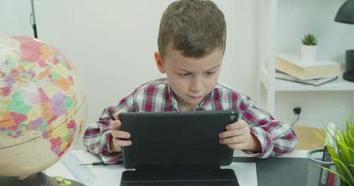 Boy Using Tablet at Desk with Globe