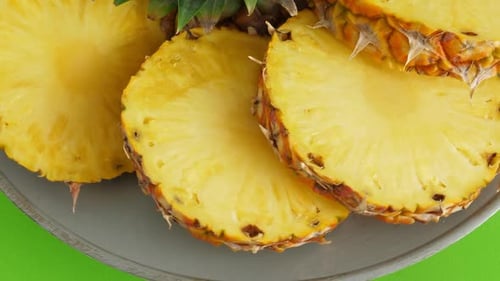 Fresh Pineapple Slices on Plate with Green Background