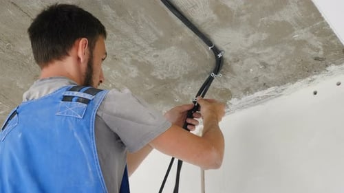 Electrician Installing Electrical Cables on Concrete Ceiling