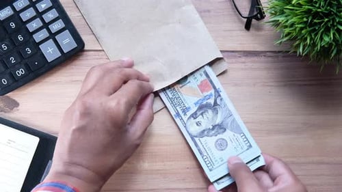 Persona que pone dinero en efectivo a mano en un sobre.