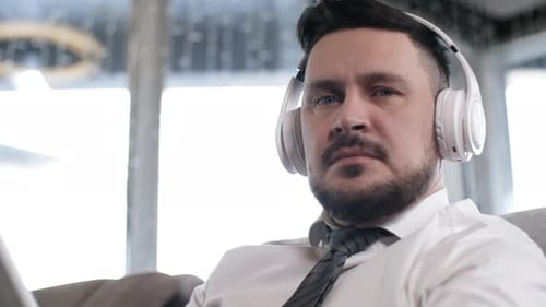 Man Listens to Tablet with Headphones on Couch