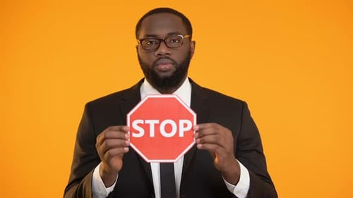 Man Holds Stop Sign in Front of Orange Background