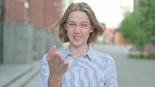 Smiling Woman Gestures to Camera in the City