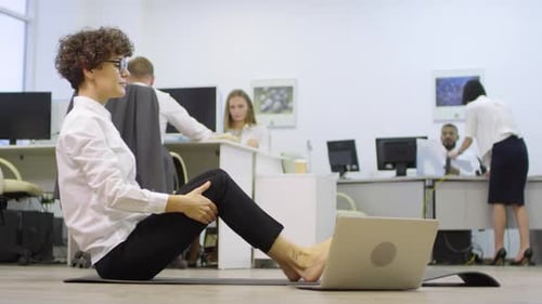 Businesswoman Stretching while Using Laptop in Office