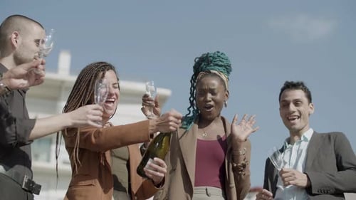 Front View of Happy Woman Opening Champagne with Coworkers