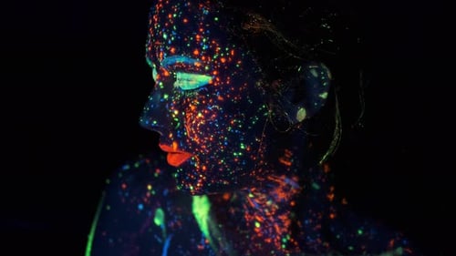 Neon Paint on the Girl's Face. Portrait of a Young Woman Painted with Luminous Paints