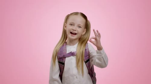 Smiling Girl with Backpack Gives OK Sign