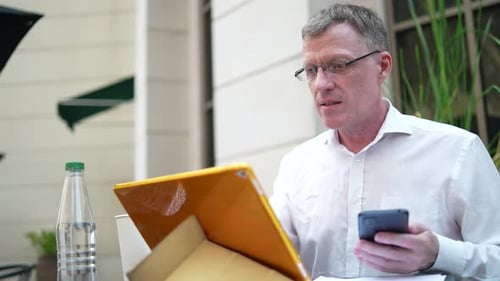 Adult Man Working Outside with Tablet and Phone