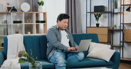 Man Working on Laptop on Sofa at Home