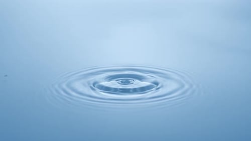 Water Drop Creates Ripple on Blue Surface