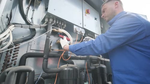 The technician checking power lines of the heat exchanger with current clamps