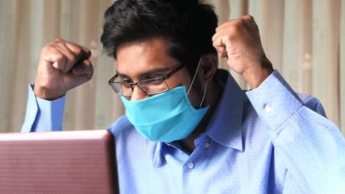 Young Adult Working On Laptop Wearing Face Mask