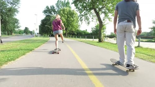 People Skateboarding on Path in Urban Park on Sunny Day