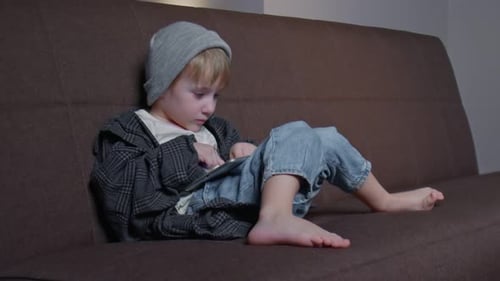 Child Plays with Tablet on a Couch