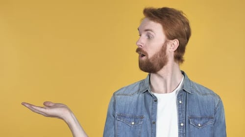Redhead Man Showing Product at Side Yellow Background