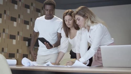 Team Discussing Blueprints in Modern Office