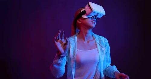 Young Asian woman playing metaverse virtual reality digital technology game with VR goggle.