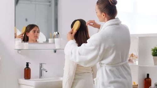 Mother Brushing Daughter's Hair in Bright Bathroom